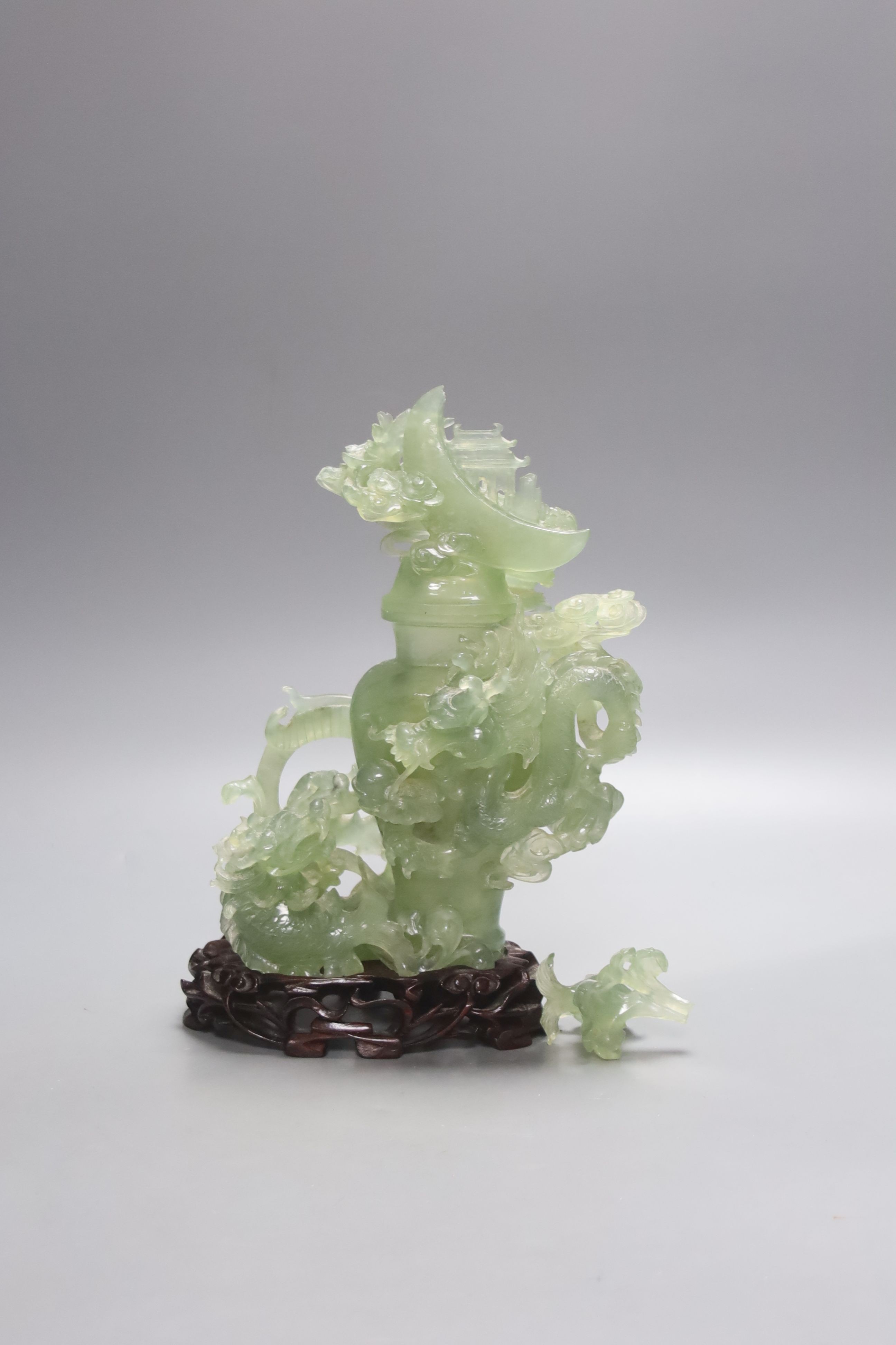 A Chinese green bowenite jade group modelled as a covered urn surrounded by a dragon, H 26cm with carved stand